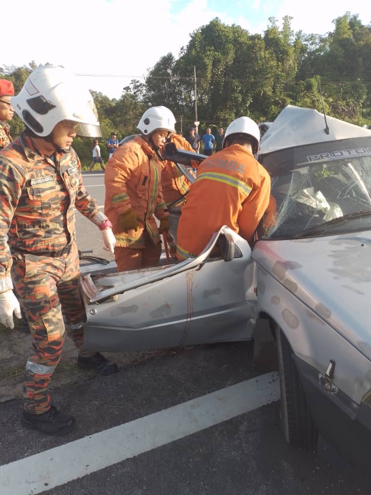 Anggota bomba sedang mengeluarkan mangsa yang tersepit di tempat duduk penumpang bahagian belakang.