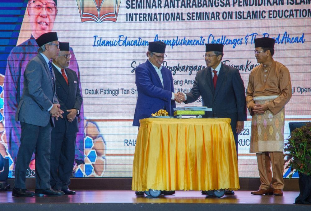 Abang Johari menerima cenderamata daripada Misnu pada Majlis Perasmian Seminar Pendidikan Islam Antarabangsa 2023 di Kuching, hari ini. - Gambar Muhd Rais Sanusi