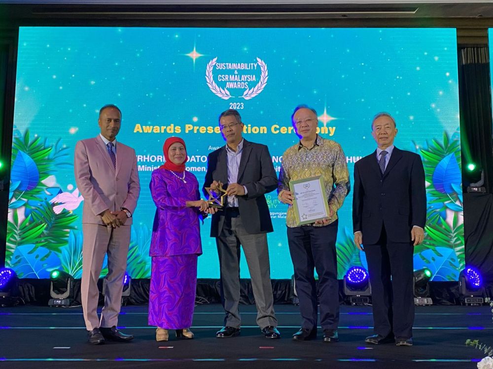 Azlam (tengah) menerima anugerah daripada Nancy Shukri, Menteri Pembangunan Wanita, Keluarga dan Masyarakat (dua kiri). 