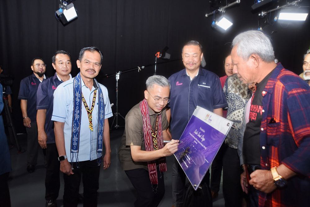Fahmi menandatangani plak perasmian Studio Sound Stage FINAS Sarawak, hari ini. - Gambar Penerangan