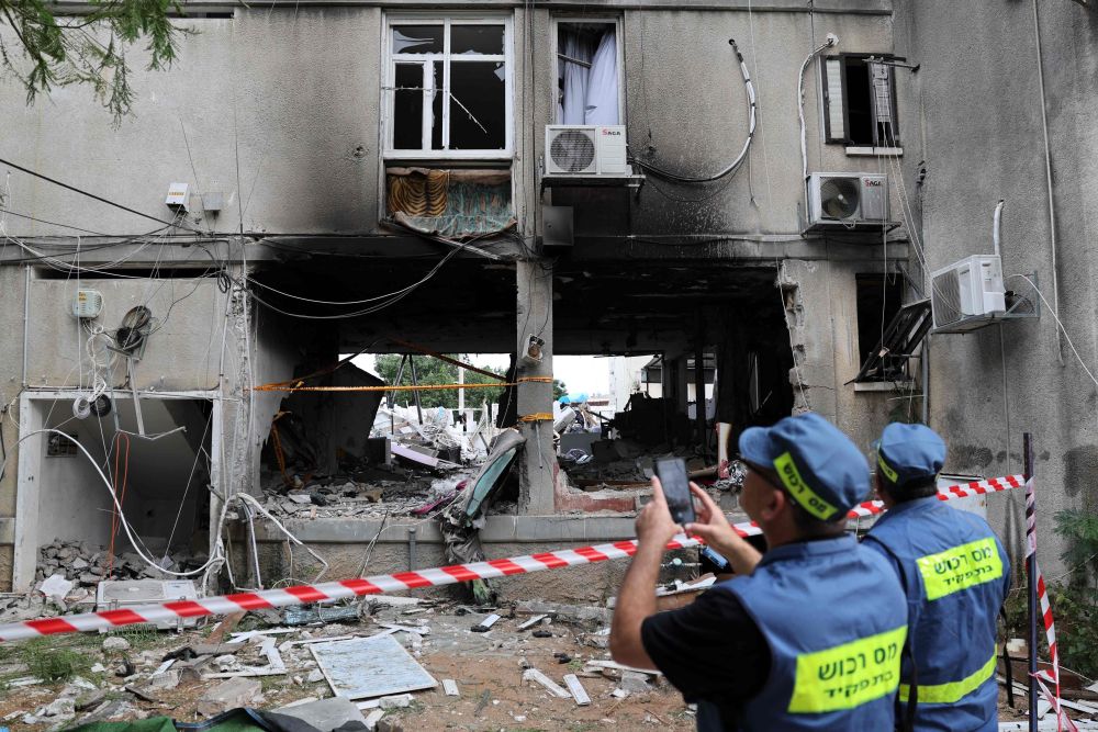 Kakitangan kecemasan semalam memeriksa kerosakan pada bangunan di bandar selatan Ashkelon yang dibedil roket dari Semenanjung Gaza kelmarin. - Gambar AFP