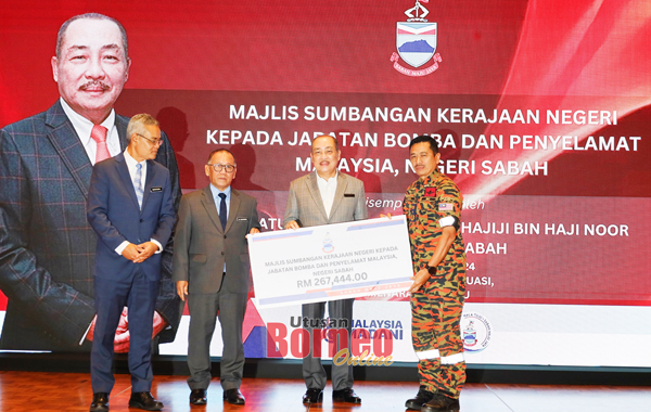  Hajiji menyampaikan sumbangan kerajaan negeri kepada Pengarah JBPM Sabah, Abdul Razak Muda.