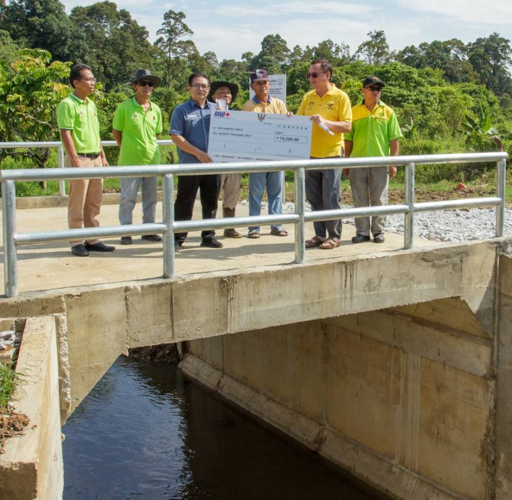 Lo (dua kanan) meyampaikan replika cek dana RTP pembinaan projek jambatan konkrit di Lorong 2, Kampung Tematu kepada Ketua Kaum Kampung Tematu Geofrey Tahang (tiga kiri) hari ini. -Gambar Mohd Faisal Ahmad