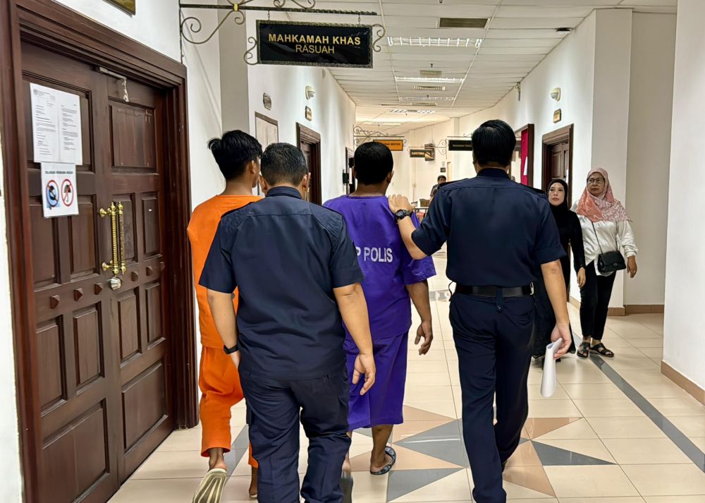 Polis mengiringi kedua-dua suspek kes ragut di Taman Desa Wira, Batu Kawa di Kompleks Mahkamah Kuching selepas permohonan reman tujuh hari ke atas mereka diluluskan hari ini. - Gambar Mohd Faisal Ahmad