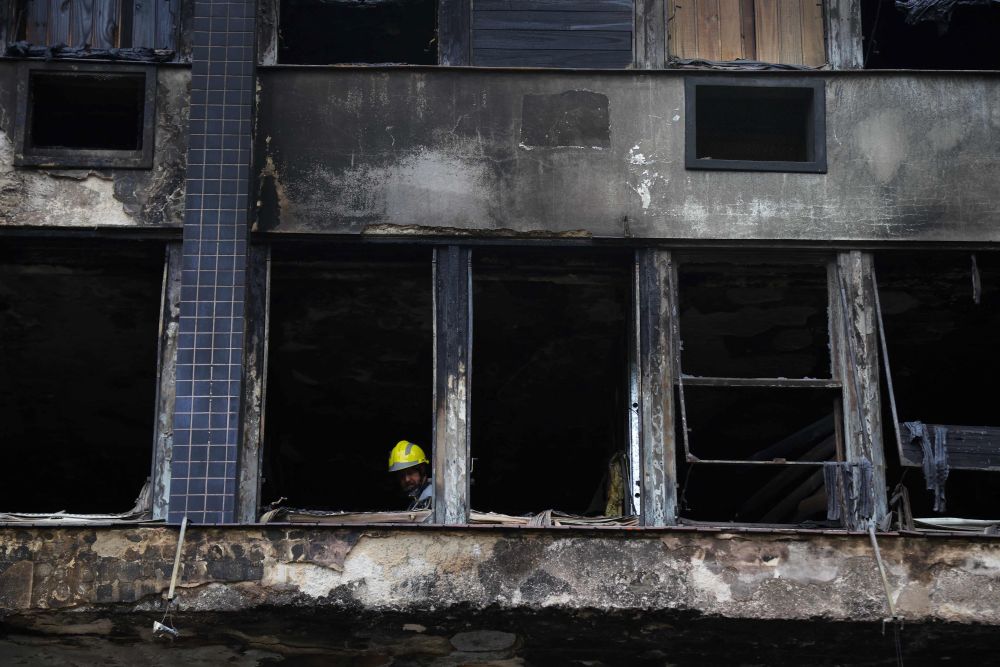 Anggota bomba berada di dalam bangunan yang separa musnah di Porto Alegre, Brazil untuk mengenal pasti punca kejadian. - Gambar AFP 