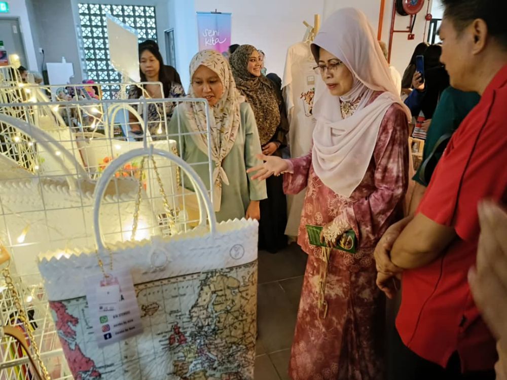 Fatimah (tengah) ditemani Dr Zufar (kanan) melihat beg straw yang unik rekaan Eureka by Azza salah satu vendor yang menyertai Seni Kita.