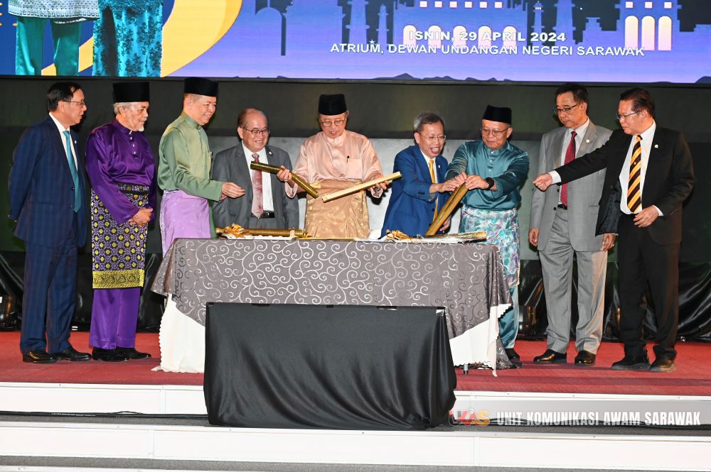 Abang Johari (lima kiri) sambil disaksikan yang lain membelah lemang sebagai simbolik perasmian Majlis Ramah-Tamah Aidilfitri anjuran Pejabat Premier Sarawak. - Gambar UKAS