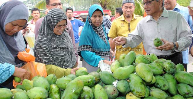 BERAPA NI?: Hasan beramah mesra bersama orang ramai ketika melawat gerai jualan mangga sempena Majlis Pelancaran Program ‘My Best Buy’ anjuran FAMA di Kuala Pilah, semalam. — Gambar Bernama