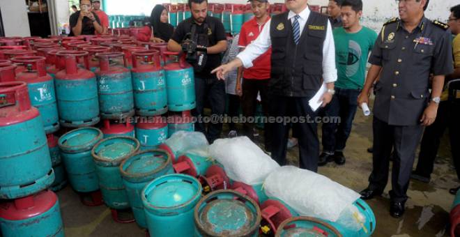 DIRAMPAS: Mohd Roslan (dua, kanan) menunjukkan sebahagian daripada 1,083 tong gas petroleum cecair (LPG), yang dirampas dari sebuah premis pemborong berlesen kerana disyaki terlibat dalam aktiviti pemindahan gas atau ‘decanting’ dari tong gas bersubsidi di Kawasan Perindustrian Bukit Indah, semalam. Turut hadir Pengarah KPDNKK negeri Abdul Rosik Yakub (kanan). — Gambar Bernama