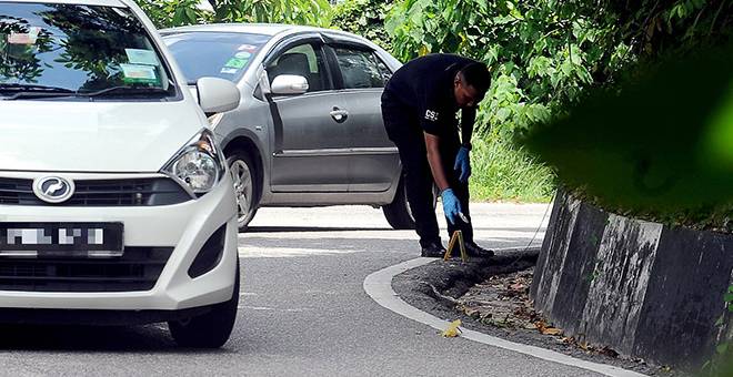 PEMERIKSAAN: Seorang anggota polis forensik melakukan pemeriksaan ke atas jalan yang dilalui sebuah kereta yang dipandu secara merbahaya di Paya Terubong dekat George Town semalam. — Gambar Bernama