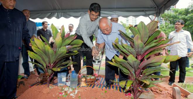 SELAMAT DIKEBUMIKAN: Sabbaruddin Chik menyiram air di pusara isteri Puan Sri Faridah Mohamed selepas selamat dikebumikan di Tanah Perkuburan Islam Bukit Kiara semalam. — Gambar Bernama