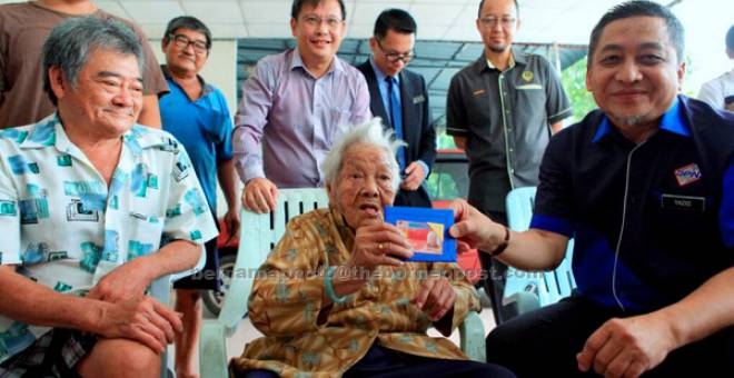 TERIMA KASIH: Warga emas Tan Kim Cheng gembira menerima kad pengenalan pemastautin tetap daripada Mohd Yazid (kanan) di Taman Pertama di Taiping, semalam. Tan, 100, dilahirkan di China pada 1917 dan datang ke Malaysia pada 1940. — Gambar Bernama