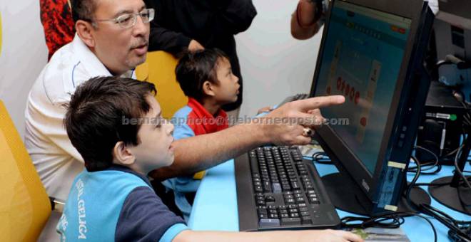 CELIK IT: Jailani melihat adik Ashfaq Hussain belajar menggunakan komputer selepas merasmikan Pusat Internet 1Malaysia Bedong di Taman Rasa Sayang di Bedong, semalam. — Gambar Bernama