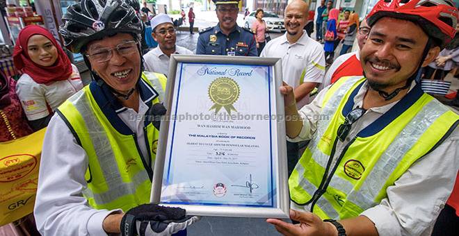 MENAMATKAN KAYUHAN: Wan Hashim (kiri) bersama Shahuri (kanan) menunjukkan sijil Malaysia Book of Records (MBOR) sebagai The Oldest To Cycle Around Peninsular Malaysia selepas berjaya menamatkan kayuhan di Kota Bharu, semalam. — Gambar Bernama