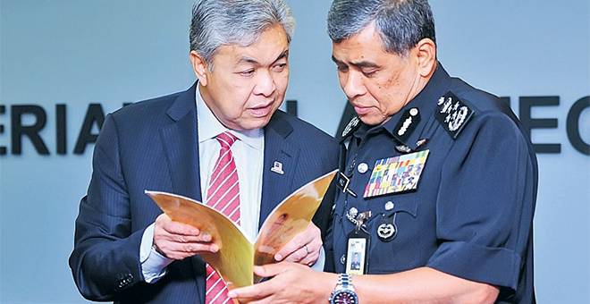 BINCANG: Ahmad Zahid (kiri) berbincang bersama Khalid sambil menunjukkan fail yang mengandungi senarai penjenayah rakyat China yang dikehendaki selepas menerima kunjungan hormat Menteri Keselamatan Awam China, Guo Shengkun di pejabatnya dekat Putrajaya, semalam. — Gambar Bernama