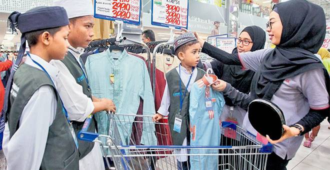 BANTU: Pelajar Universiti Tun Abdul Razak (UNIRAZAK) Nur Amira (kanan) bersama rakannya Alia Maisarah Tajul Arifin (dua kanan), membantu kanak-kanak Madrasah Hashimiah membeli persiapan Aidilfitri ketika program ‘Raya Shopping Spree’ anjuran Yayasan Noha dan UNIRAZAK di Mydin Subang Jaya dekat Kuala lumpur, semalam. — Gambar Bernama