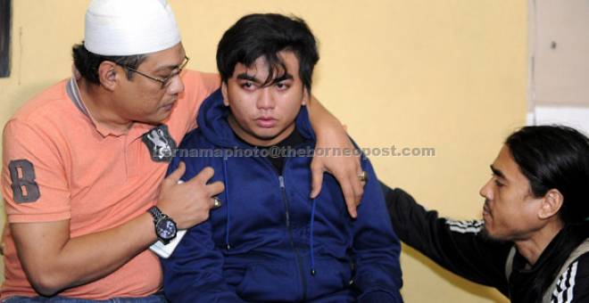 REDA: Wan Muhammad Hazim Wan Mohd Fauzi, 19 (tengah), ditenangkan oleh anggota keluarga ketika tiba di Hospital Jempol malam kelmarin untuk melihat jenazah ibu bapa serta semua empat adik beradiknya yang turut maut dalam kemalangan membabitkan tiga kenderaan dan sebuah treler di KM25 jalan Bahau-Keratong kelmarin. — Gambar Bernama