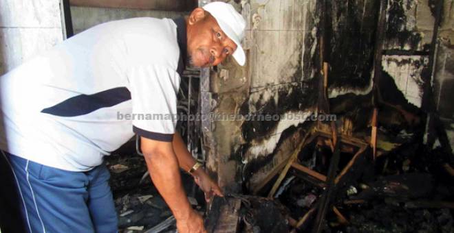 MUSNAH: Abdullah menunjukkan bahagian stor yang terbakar dalam kejadian petang kelmarin. — Gambar Bernama