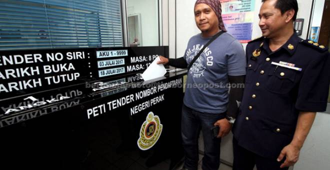 MENDAPAT SAMBUTAN: Ridzuan (kanan) memerhatikan pembida terakhir nombor pendaftaran AKU, Alfizan Satiman, 40, memasukkan borang tender pada waktu terakhir tempahan nombor pendaftaran kenderaan siri AKU di Ibu Pejabat JPJ negeri di Ipoh semalam. — Gambar Bernama