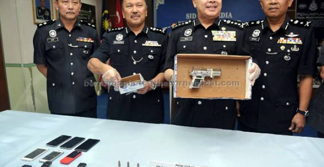 DIRAMPAS: Wan Ahmad (dua kanan) dan Mohd Kamarudin (dua kiri) menunjukkan pistol semiauto jenis CZ dan satu kelopak bersama tiga butir peluru hidup jenis 9mm yang dirampas dengan tertangkapnya tiga warga tempatan di Ibu Pejabat Polis Kontinjen Johor Bahru, semalam. — Gambar Bernama