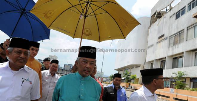 PRIHATIN: Tengku Abdullah berkenan melawat tangki yang pecah di atas bangunan Kompleks Teruntum yang memecahkan tembok konkrit di Kuantan semalam. Turut hadir Adnan (kanan)             dan Muhammad Safian (kiri). — Gambar Bernama