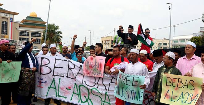 BANTAHAN: Mohd Ali (berdiri belakang) melaungkan ‘hancur-hancur Israel’ ketika bersama membantah perlakuan Zionis Israel yang menghalang kemasukan umat Islam ke Masjid Al-Aqsa selepas solat jumaat di hadapan perkarangan Masjid Al-Azim Bukit Palah, Melaka, semalam. — Gambar Bernama