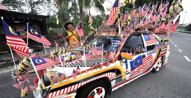 SEMANGAT KEMERDEKAAN: Taza membetulkan bendera yang dipasang pada kenderaannnya ketika ditemui Bernama semalam. — Gambar Bernama