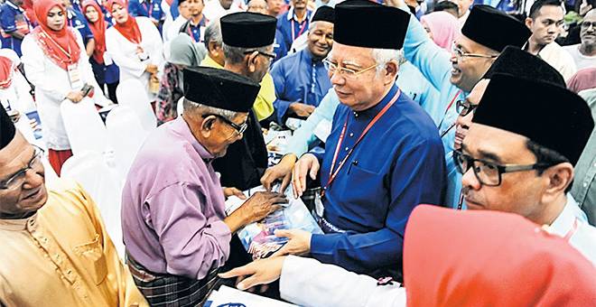 TERIMALAH: Najib (tengah) menyampaikan sumbangan kepada veteran UMNO pada Majlis Perasmian Persidangan Perwakilan UMNO Bahagian Langkawi di Pusat Pameran Antarabangsa Mahsuri (MIEC) dekat Langkawi. — Gambar Bernama