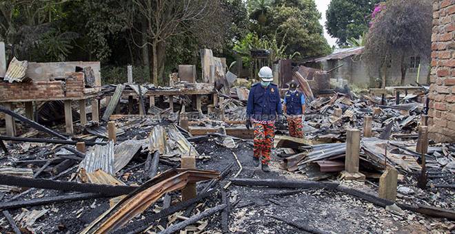 KUMPUL BUKTI: Unit Forensik Bomba dan Penyelamat melakukan siasatan terhadap kejadian kebakaran melibatkan dua puluh unit rumah setinggan di Wakaf Mek Zainab dekat Kota Bharu, semalam. — Gambar Bernama