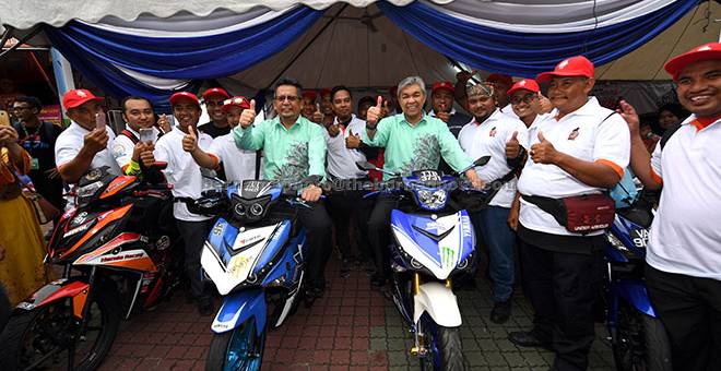 CUBA: Ahmad Zahid (kanan) dan Ahmad Razif mencuba motosikal yang dipamerkan sewaktu melawat gerai pameran selepas merasmikan Karnival Pertubuhan Kebangsaan 2017 di Dataran Batu Burok dekat Kuala Terengganu, semalam. — Gambar Bernama
