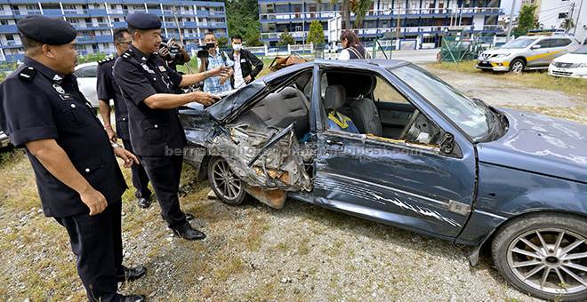 TRAGIS: Supt Som (dua kiri) menunjukkan kereta Proton Iswara yang turut terlibat dalam kes kemalangan di antara sebuah lori membawa ais dan van yang meragut sembilan nyawa di Mambang Di Awan dekat Kampar Sabtu lalu. — Gambar Bernama