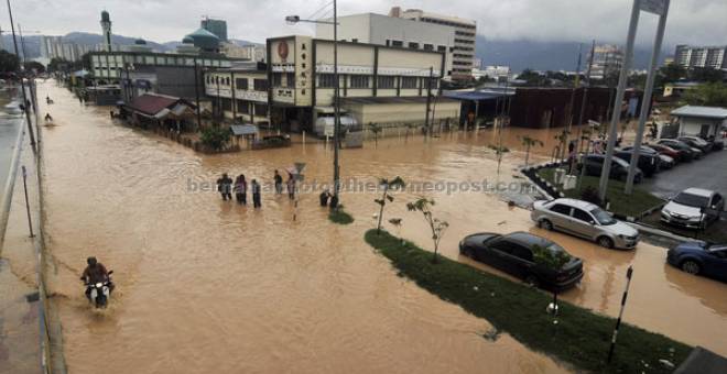 REDAH: Orang ramai mengharungi banjir kilat berikutan hujan lebat sejak tengah hari kelmarin di Jalan Sungai Pinang, Jelutong semalam. — Gambar Bernama