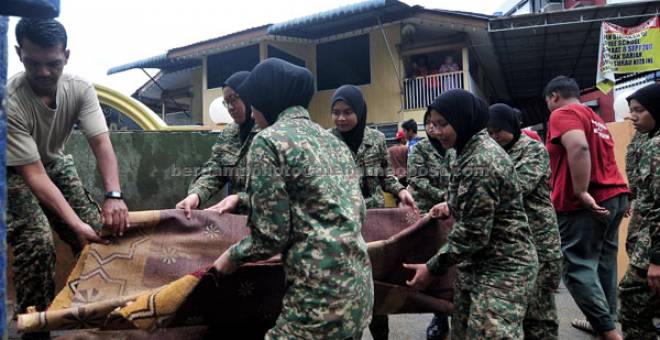 GOTONG-ROYONG: Anggota Askar Wataniah membuang tikar surau yang musnah akibat banjir kelmarin di Taman Penang Free School semalam. — Gambar Bernama