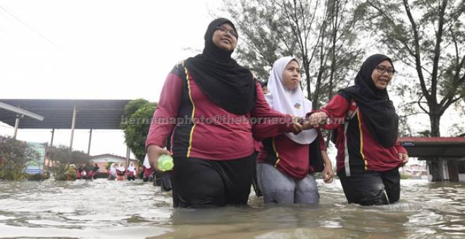 REDAH: Pelajar Sekolah Menengah Kebangsaan Datuk Haji Ahmad Said mengharungi banjir untuk menduduki peperiksaan Sijil Pelajaran Malaysia di sekolah itu dekat Sungai Dua, semalam. — Gambar Bernama 