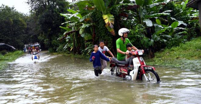 BANJIR: Kelihatan penduduk meredah air banjir apabila kampung mereka dinaiki air apabila hujan lebat berterusan semenjak dua hari lepas di Kampung Hutan Pasir Ketereh semalam. — Gambar Bernama