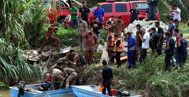 DIJUMPAI: Anggota Bomba dan Penyelamat mengusung mayat terakhir iaitu Rapawi di tebing sungai berhampiran simpang empat Puncak Alam ketika operasi mencari dan menyelamat di Sungai Gasi, Sungai Buloh di Puncak Alam, semalam. — Gambar Bernama