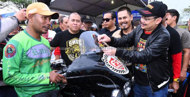 KEMPEN: Dzulkifli menampal pelekat bebas rasuah pada majlis SPRM bersama Bikers di Tapak Ekspo Pertanian Malaysia (MAEPS) dekat Serdang, semalam. Turut hadir Pengasas Ikatan Silaturahim Brotherhood Azlan Sani Zawawi atau lebih dikenali sebagai Lando (dua kanan). — Gambar Bernama