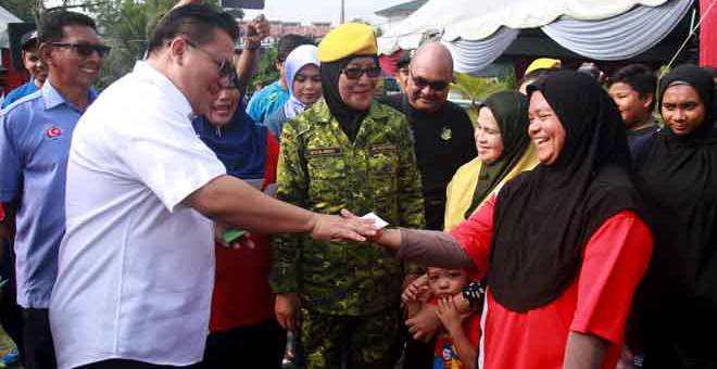 GIMIK: Nur Jazlan (dua kiri) yang juga Ahli Parlimen Pulai mengagihkan kupon gula percuma sebagai gimik perasmian Program Jualan Sentuhan Rakyat Parlimen Pulai di Taman Perling, Johor Bahru, semalam. — Gambar Bernama