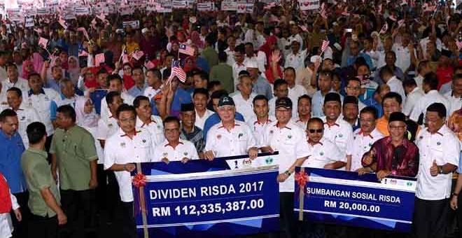 AGIH DIVIDEN: Najib (depan tengah) ceria memegang replika cek berupa dividen yang bakal diagihkan kepada para pekebun ketika hadir menyampaikan Dividen Risda Peringkat Nasional 2018 di Kampung Peragap di Temerloh semalam. — Gambar Bernama