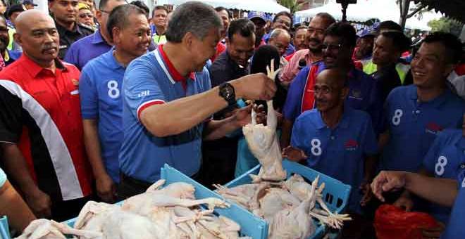 LELONG: Zahid (tiga kiri) turut membantu mempromosikan jualan lelong ayam dengan harga RM5 sekilogram ketika tinjauan mesra sempena Program Jualan Sentuhan Rakyat di Perkarangan Wisma UMNO Hutan Melintang semalam. — Gambar Bernama