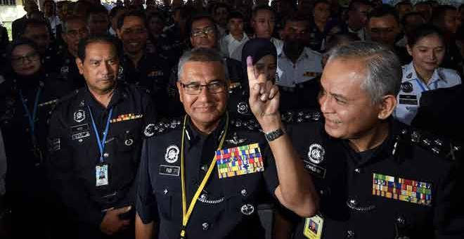 SUDAH UNDI: Mohamad Fuzi (tengah) menunjukkan jarinya yang telah dicelup dengan dakwat selepas pengundian awal bagi Pilihan Raya Umum Ke-14 di Ibu Pejabat Polis Bukit Aman di Kuala Lumpur semalam. — Gambar Bernama