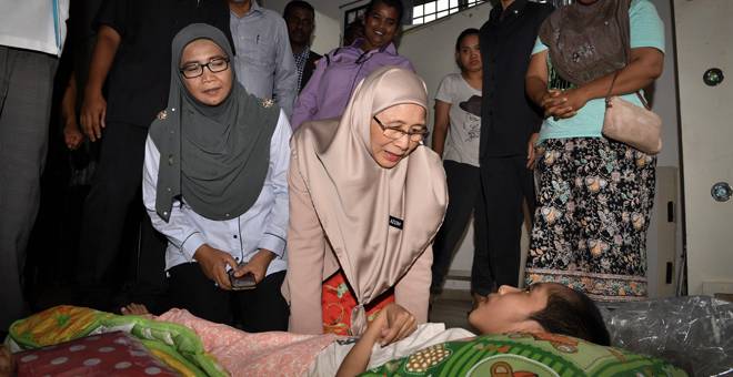 PRIHATIN: Wan Azizah (tengah) menziarahi Mohd Abdul Hanif Mohd Abdul Rashid, 12, yang menghidap penyakit ‘Cerebral Palsy’ semasa melawat mangsa kebakaran di Dewan Pandan Baiduri              Taman Maluri di Kuala Lumpur semalam. — Gambar Bernama