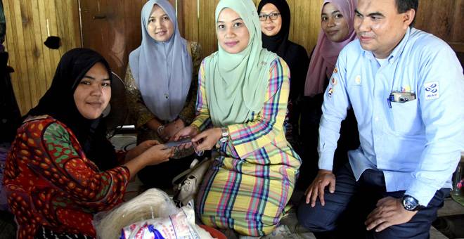 SUMBANGAN AIDILFITRI: Rosiana (kiri) menerima sumbangan Aidilfitri pada Program KAWAT Prihatin di Kampung Padang Kemunting, Batu Rakit di Kuala Terengganu semalam. — Gambar Bernama