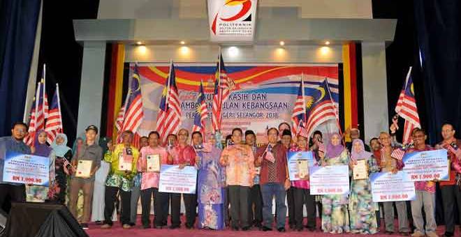 SEMANGAT PATRIOTIK: Dr Md Farid (tengah)  bergambar bersama pemenang Anugerah Perdana Rukun Tetangga Negeri Selangor 2018 sambil mengibarkan Jalur Gemilang pada Majlis Tautan Kasih dan Sambutan Bulan Kebangsaan Peringkat Negeri Selangor 2018 di Politeknik Sultan Salahuddin Abdul Aziz Shah, semalam. — Gambar Bernama