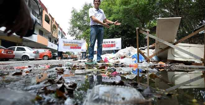 KOTOR: Tan (tengah) menunjukkan takungan air dan sampah yang terbiar pada sidang media mengenai kes denggi yang berleluasa di Batu 9 Cheras di Kuala Lumpur semalam. — Gambar Bernama