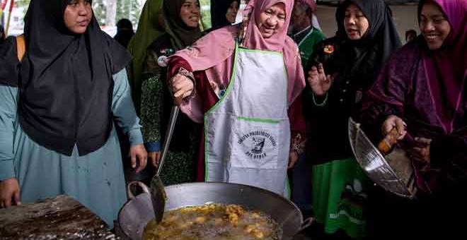 BEGINI CARANYA: Halimah (tengah) melakukan demonstrasi masakan ketika berkempen dengan penduduk setempat pada Program ‘Jom Makan Buah- Buahan Tempatan’ di Padang PPRT Lembah Subang dekat Subang, semalam. — Gambar Bernama