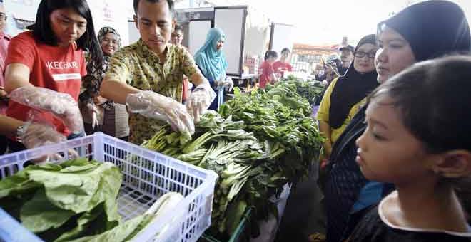 PERCUMA: Ahmad Fahmi (dua kiri) menyusun sayuran yang diberikan secara percuma kepada penduduk setempat melalui Kechara Soup Kitchen (KSK) pada program My Community Care 2018 di Dataran Seri Angkasa, Kuala Lumpur semalam. — Gambar Bernama