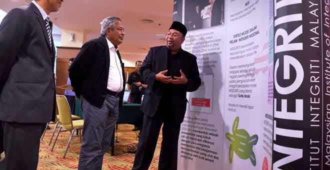 INGIN TAHU: Muhammad Safian (tengah) mendengar penerangan daripada Hamilye (kanan) ketika melawat pameran selepas merasmikan Seminar Pemerkasaan Integriti Negeri Pahang, Kuantan semalam. — Gambar Bernama