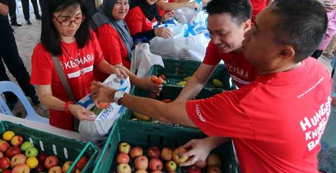 BUNGKUS MAKANAN: Sukarelawan membungkus bahan makanan ke dalam beg plastik sebelum di serahkan kepada penerima pada Projek Perintis Program Food Bank Malaysia Peringkat Negeri Melaka, semalam. — Gambar Bernama