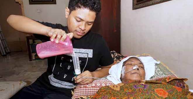 KASIH ANAK: Mohd Khairul (kiri) memberi susu kepada Siti yang terlantar sakit di rumah mereka di Taman Sri Permai, Alor Setar semalam. — Gambar Bernama